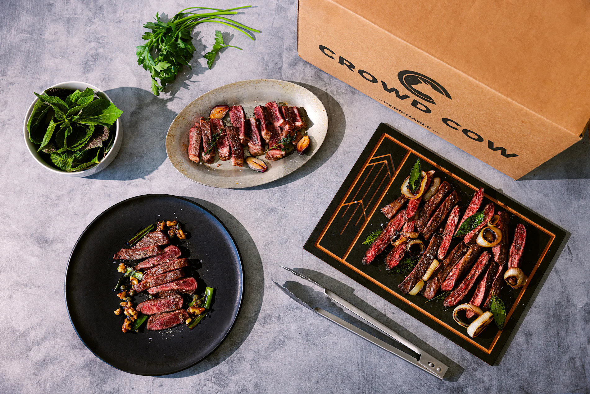 A Crowd Cow box surrounded by plated dishes, shot from above