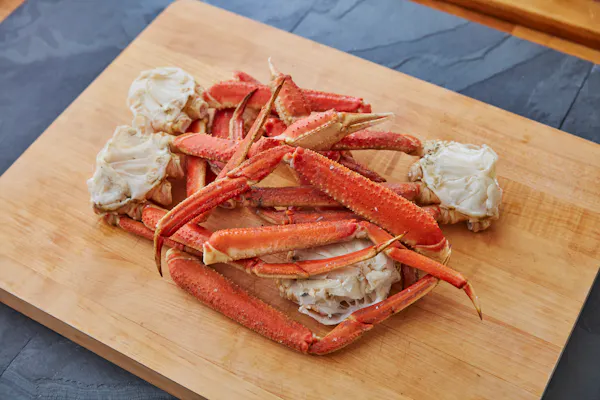 Cooked snow crab legs piled on a wooden cutting board