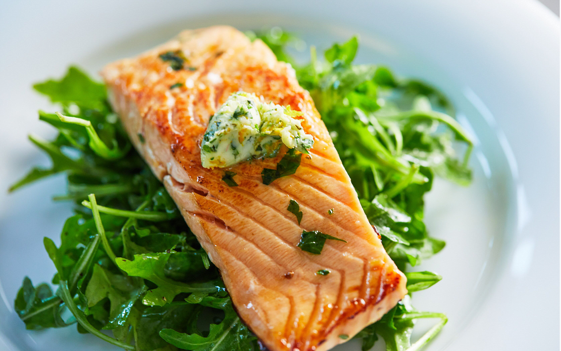 Seared citrus salmon fillet served over dressed arugula with herb butter