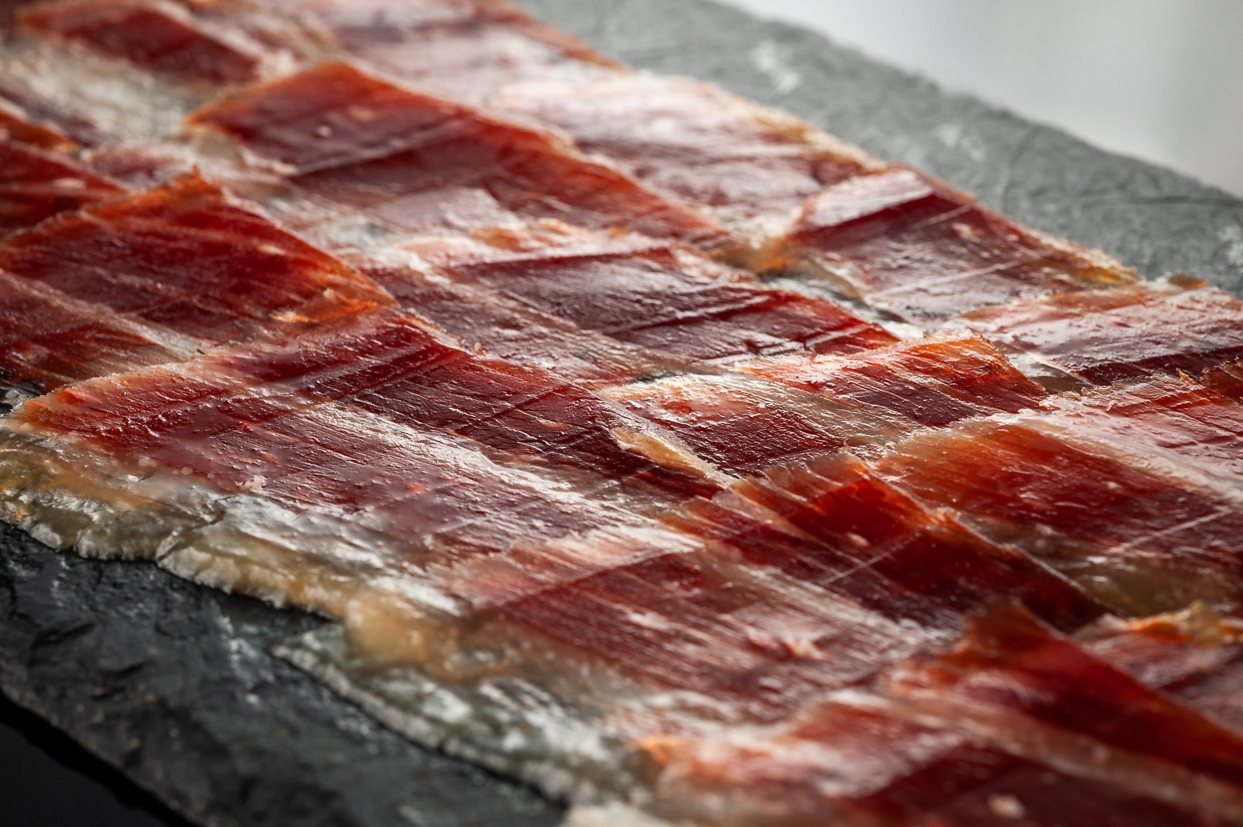Thin slices of Fermin jamon iberico laid across slate