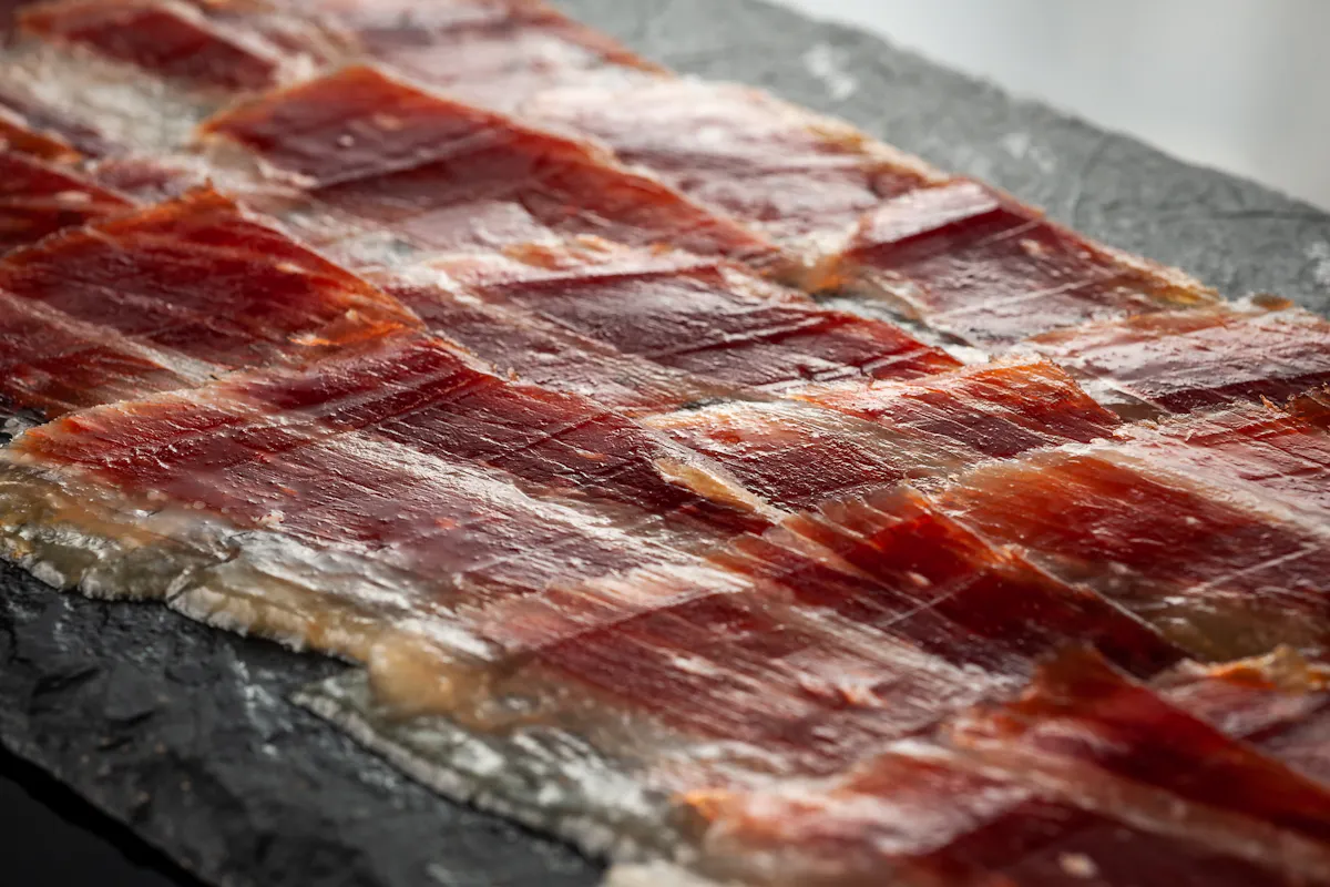 Thin slices of Fermin jamon iberico laid across slate