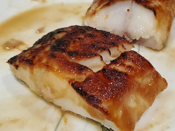 Close-up of miso-glazed black cod with a caramelized crust and large flakes of white fish