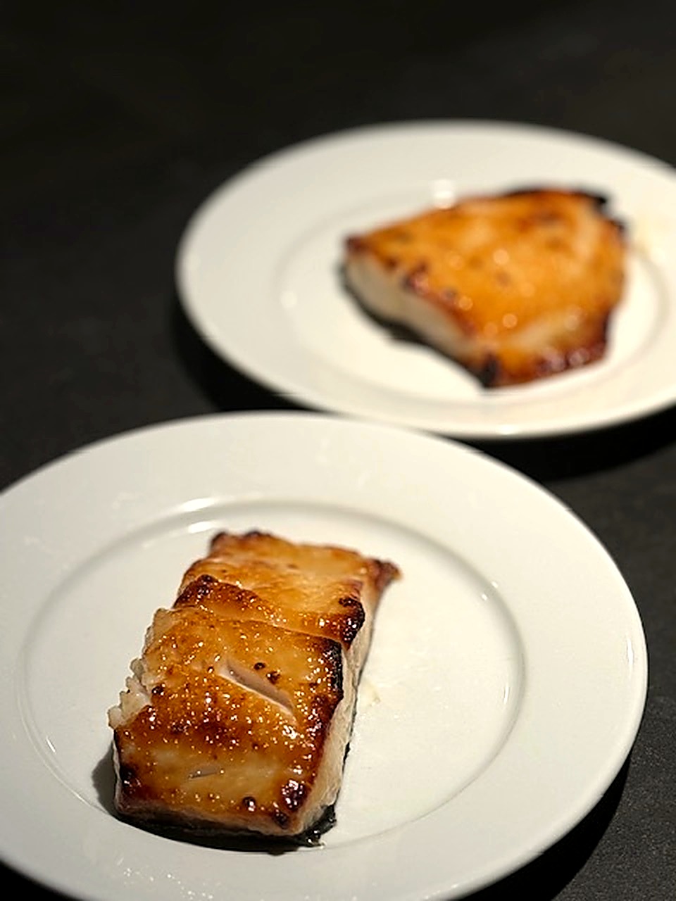 Miso-glazed black cod with a caramelized top on a white plate