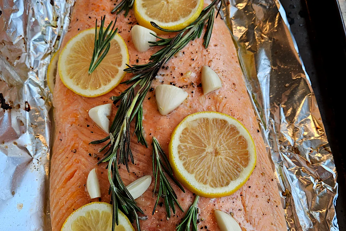A whole side of Ōra King salmon baked in foil with lemon slices, rosemary and garlic