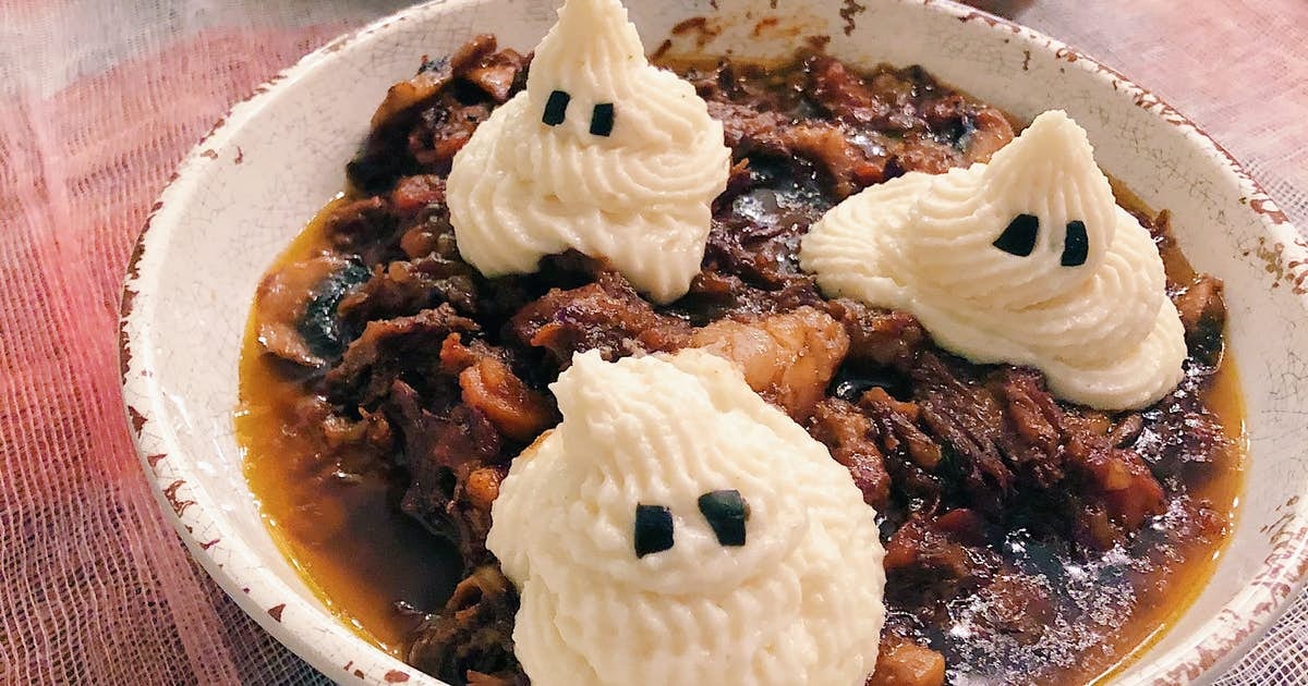 A bowl of beef short rib stew topped with three piped mashed potato ghosts