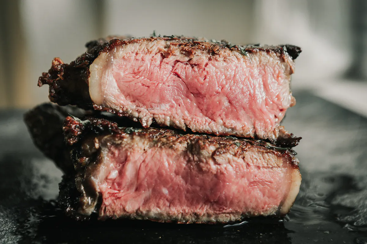 Two stacked slices of medium-rare steak with a dark seared crust