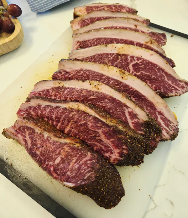 Sliced, seasoned Margaret River Wagyu picanha steaks showing heavy marbling and a thick fat cap, on a white cutting board