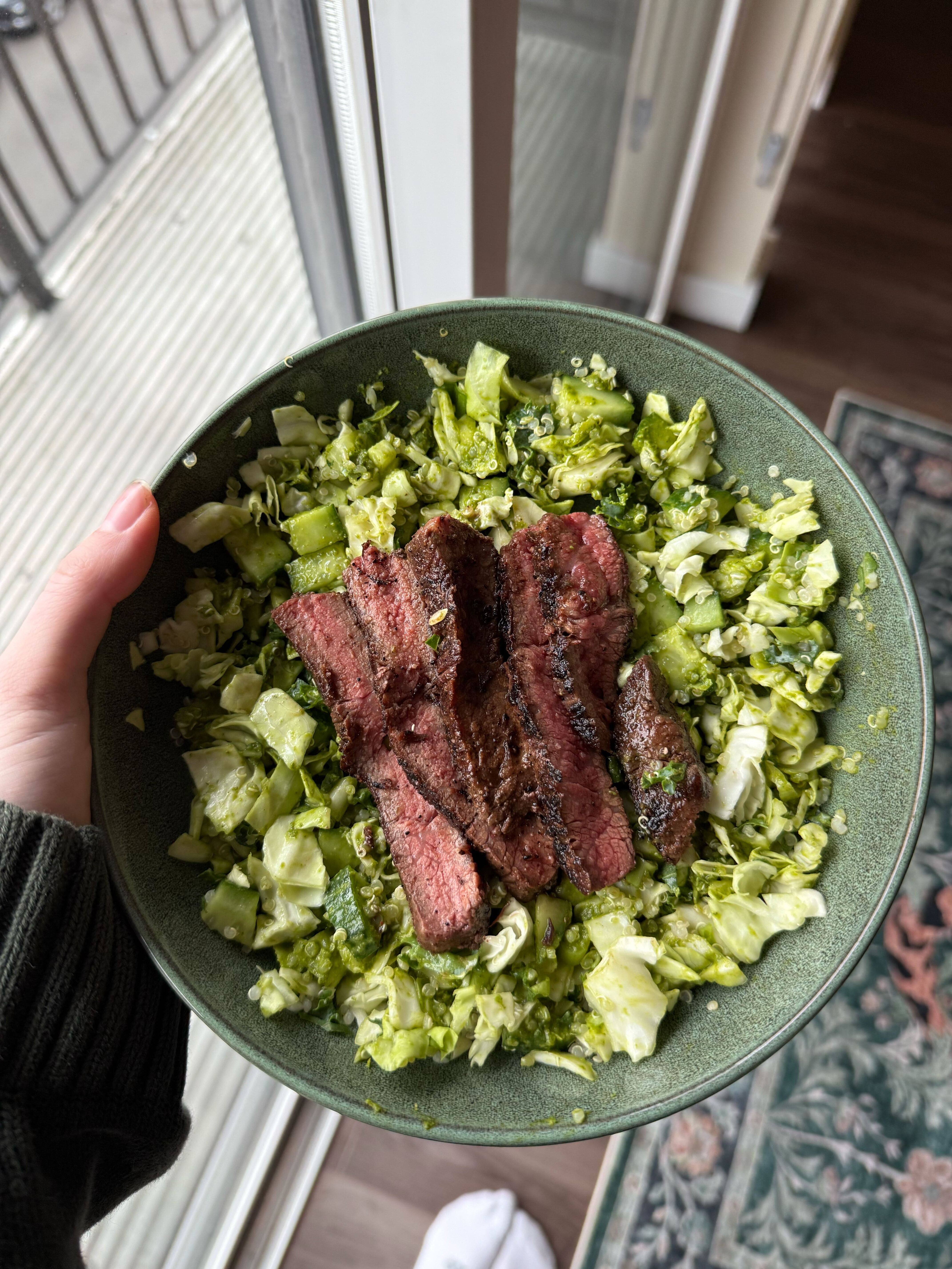 Sliced Denver steak over a bowl of chopped green salad