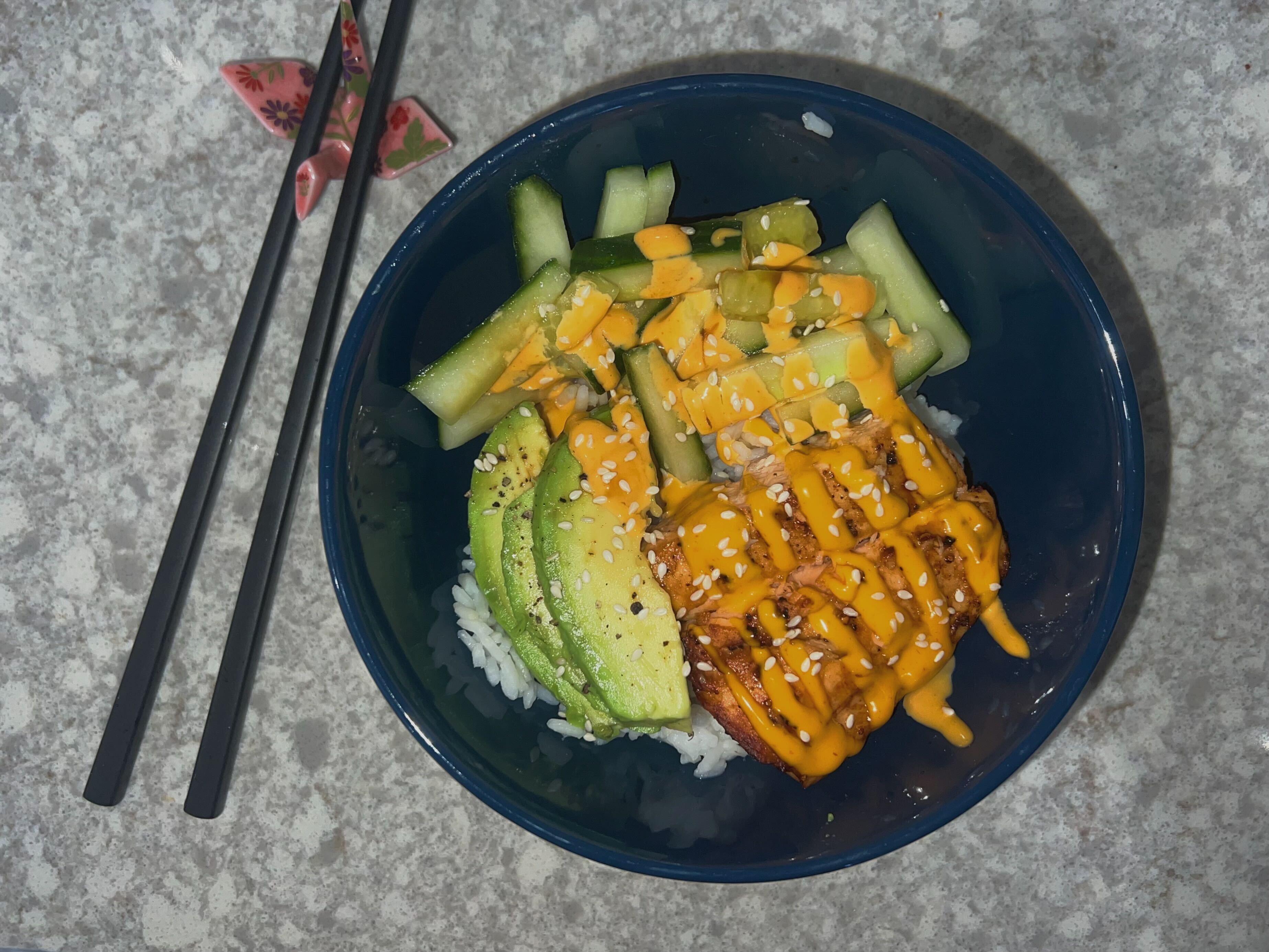A salmon sushi bowl with rice, avocado, cucumber and spicy mayo
