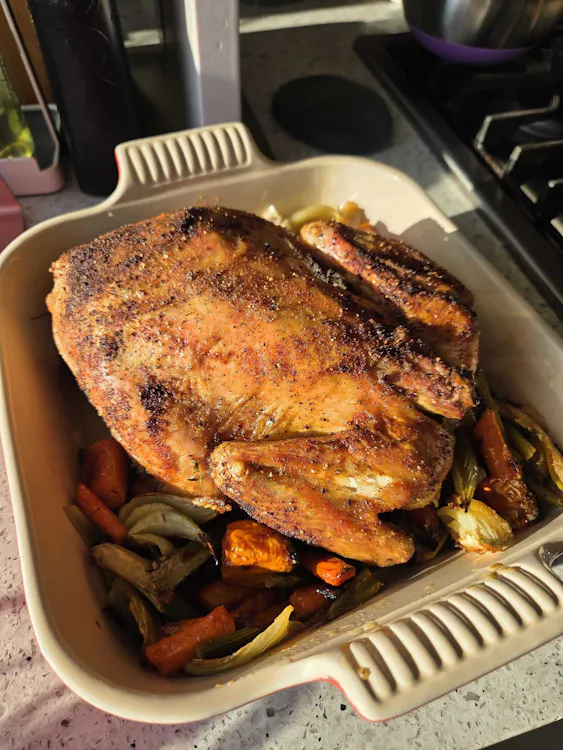 A golden roasted Poulet Rouge chicken over autumn vegetables