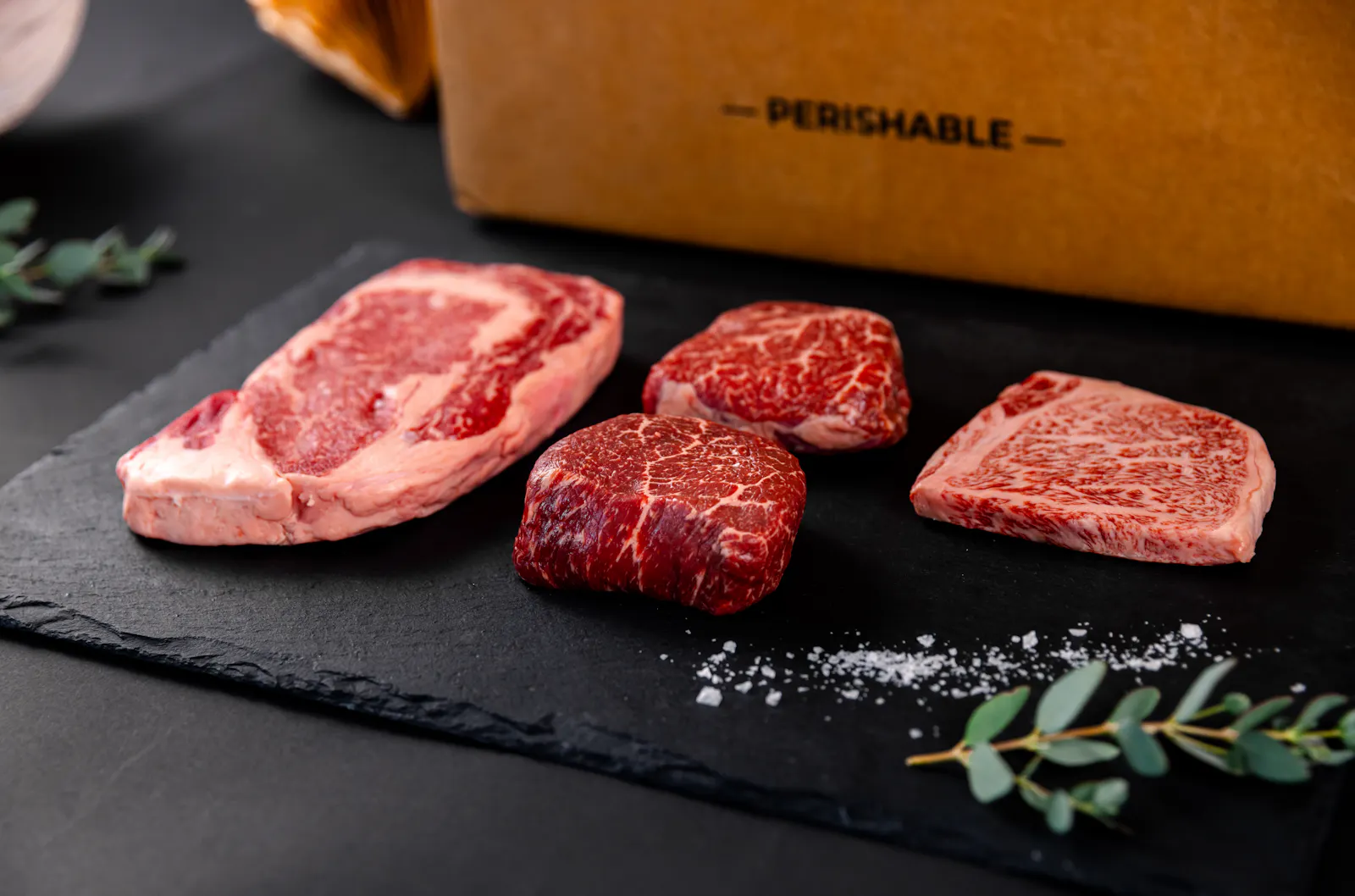 Wagyu steaks on a slate board beside a Crowd Cow box