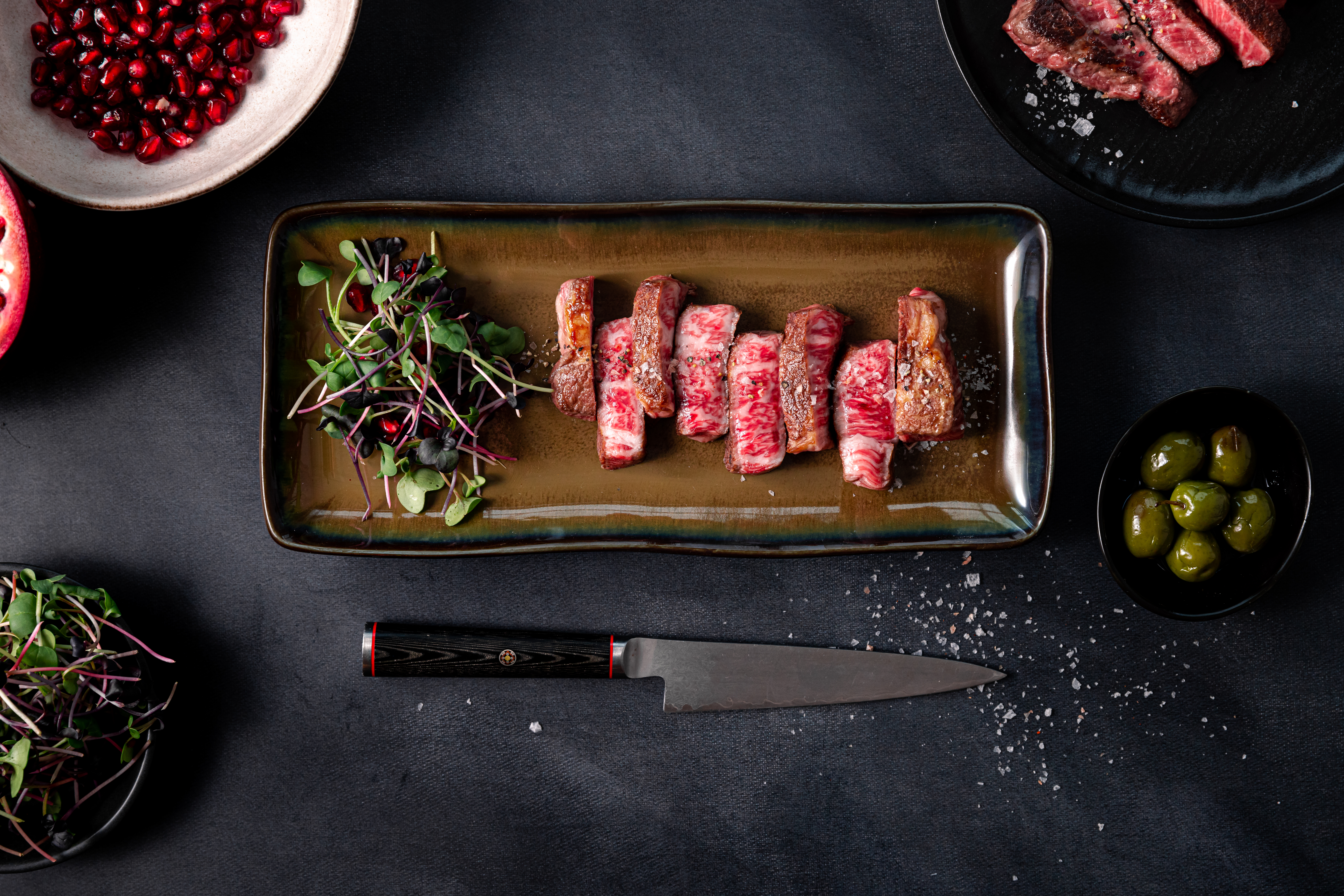 Sliced, heavily marbled A5 Wagyu on a long platter with microgreens
