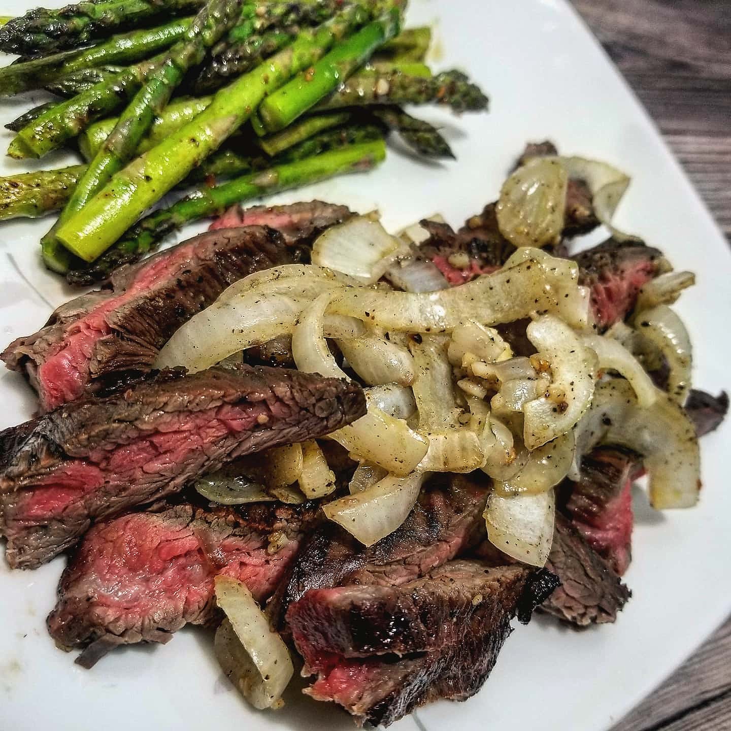 Sliced flank steak topped with sauteed onions, served with roasted asparagus