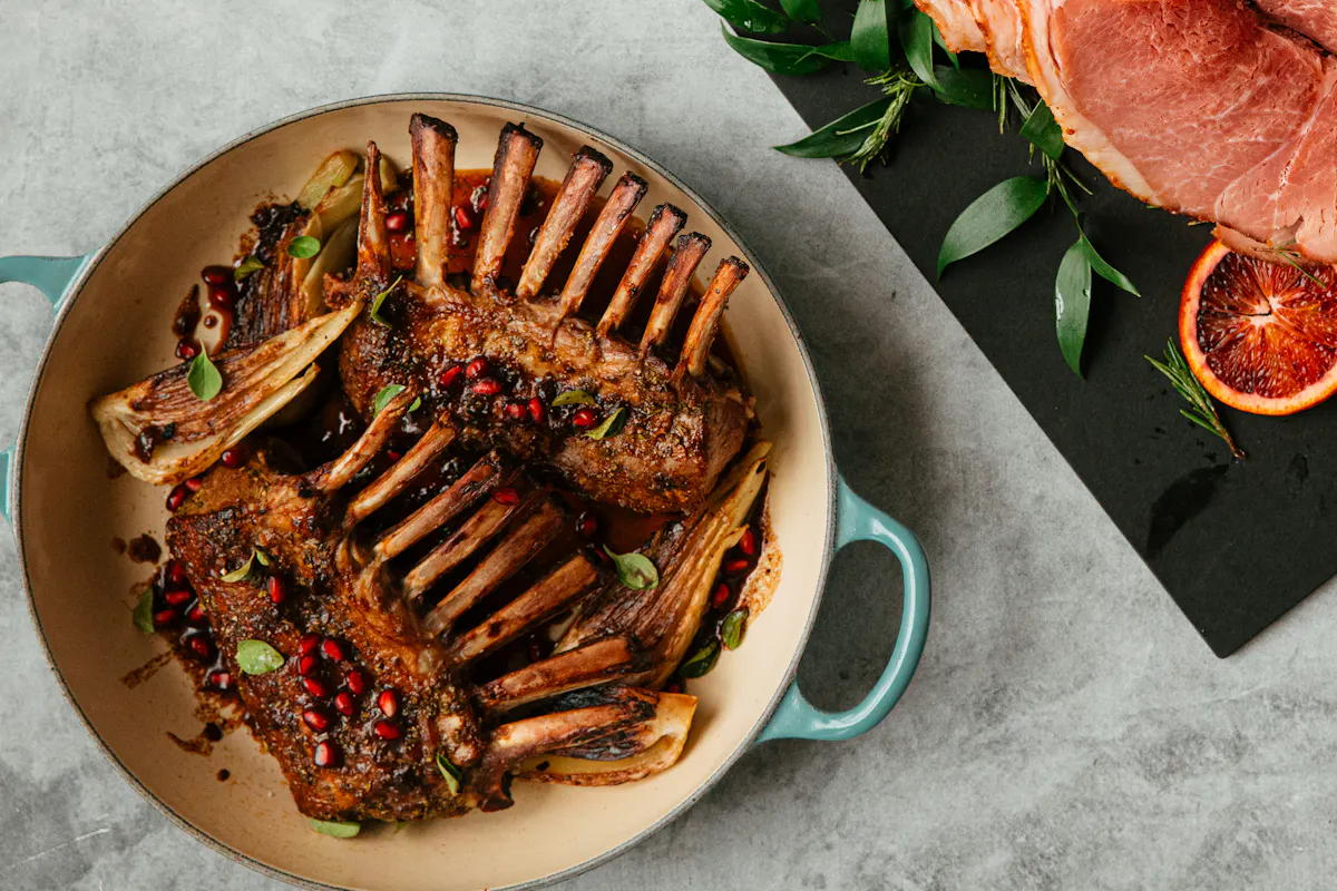 Roasted frenched lamb racks with pomegranate seeds in a cream dish