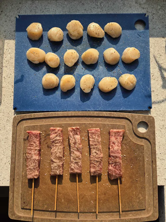 Raw Hokkaido scallops above five A5 Wagyu striploin skewers